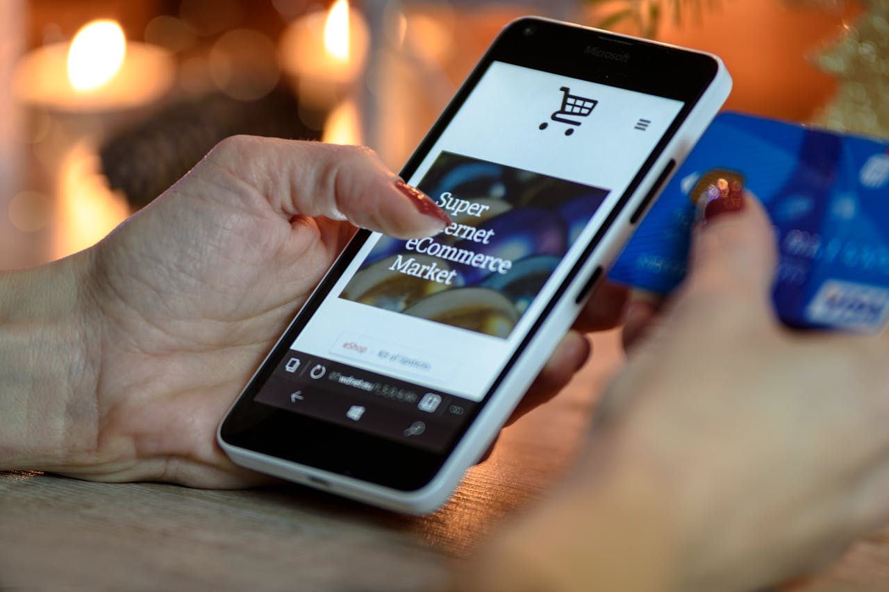 heros-img Woman using smartphone for online shopping with credit card in hand, festive background lighting.