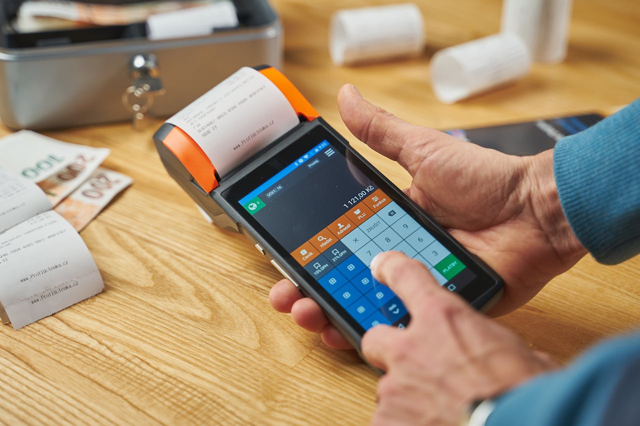 who-we-are Close-up of hands operating a modern point of sale device with a printed receipt.