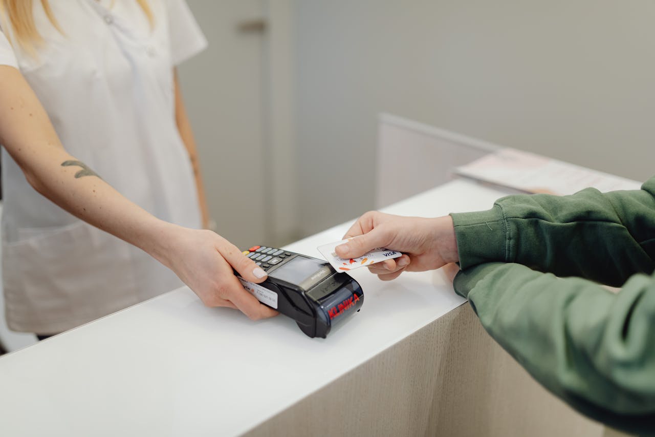 services-04 Person using a bank card for contactless payment at a modern checkout counter.