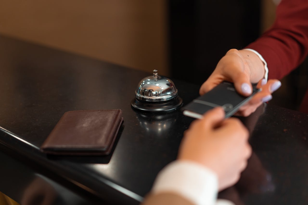 about-us A close-up of a hotel check-in process with a smartphone and card transaction at the reception desk.